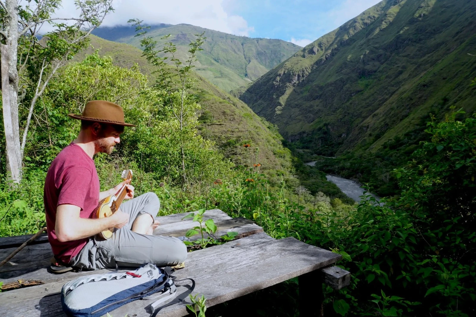 Un hombre tocando un charango en una plataforma de madera construida sobre el valle