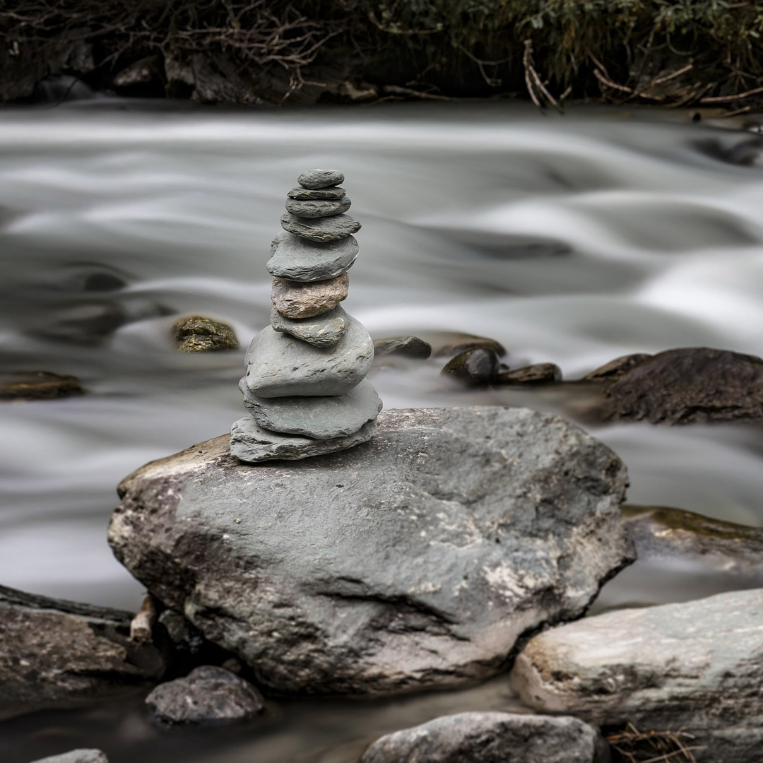 Torre de piedras en equilibrio junto al agua, emblema del curso Alchemy of Immortality Qigong